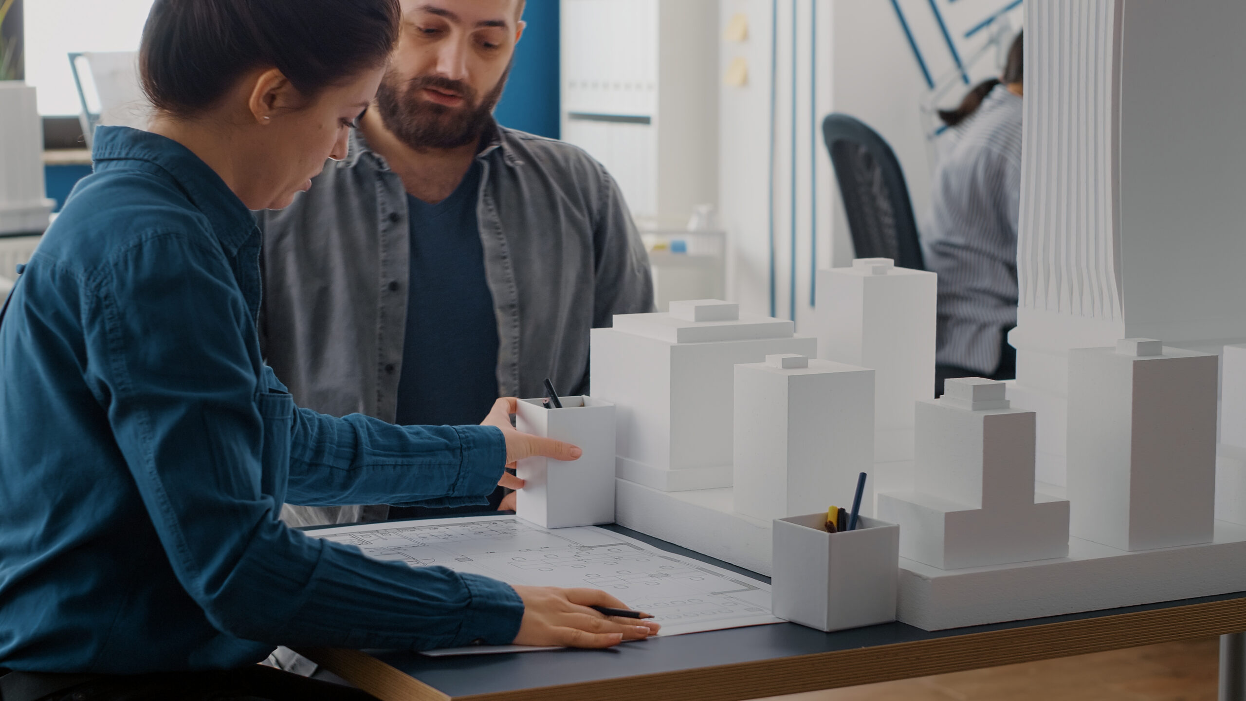 close up of man and woman designing blueprints plan, analyzing building model